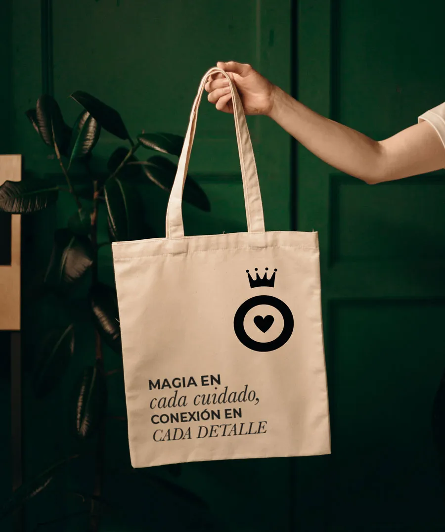 Tote bag with the crown logo and the line “Magic in every treatment, connection in every detail”